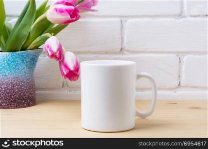 White coffee mug mockup with pink tulip in purple blue vase. Empty mug mock up for design promotion.