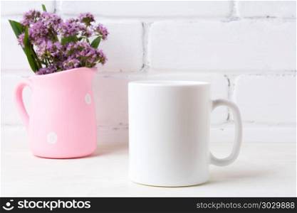 White coffee mug mockup with purple flowers in polka dot pink pi. White coffee mug mockup with purple field flowers in polka dot pink rustic pitcher vase. Empty mug mock up for design promotion.