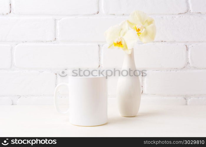 White coffee mug mockup with soft yellow orchid in vase. Empty mug mock up for design promotion. . White coffee mug mockup with soft yellow orchid in vase
