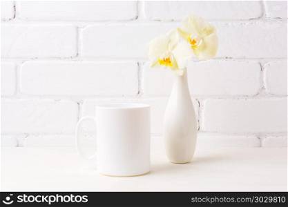 White coffee mug mockup with soft yellow orchid in vase. Empty mug mock up for design promotion. . White coffee mug mockup with soft yellow orchid in vase