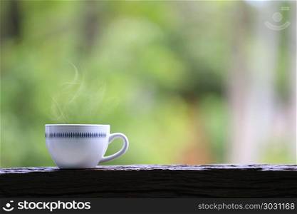 White coffee mug on wooden floor and green nature background.. White coffee mug on wooden floor and green nature background for design in your work.