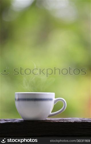 White coffee mug on wooden floor and green nature background for design in your work. . White coffee mug on wooden floor and green nature background.