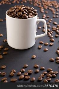 white coffee mug with coffee grains on a black background with coffee grains