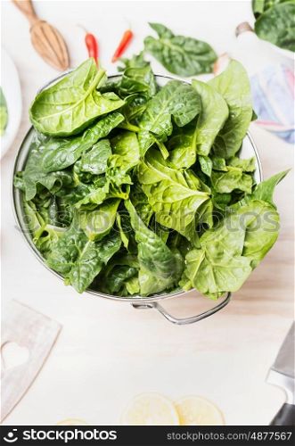 White Colander with fresh green organic spinach leaves, close up. Vegan or vegetarian nutrition, diet, detox and healthy food concept