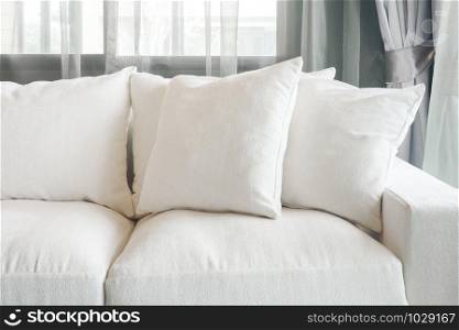 White color sofa and pillows with sheer curtain in background