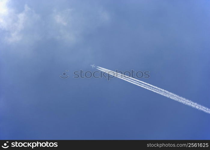 White Condensation Trail From A Commercial Airplane As It Flies Across A Blue Sky