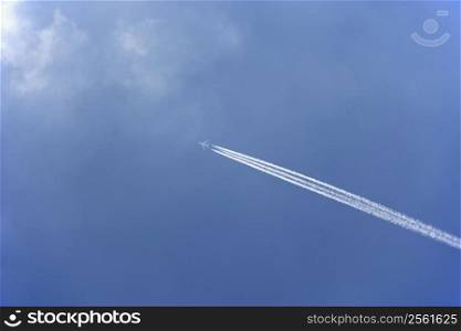 White Condensation Trail From A Commercial Airplane As It Flies Across A Blue Sky