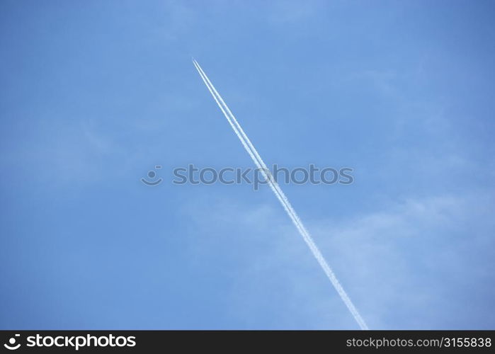 White Condensation Trail From A Jet As It Flies Across A Blue Sky