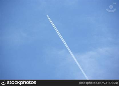 White Condensation Trail From A Jet As It Flies Across A Blue Sky