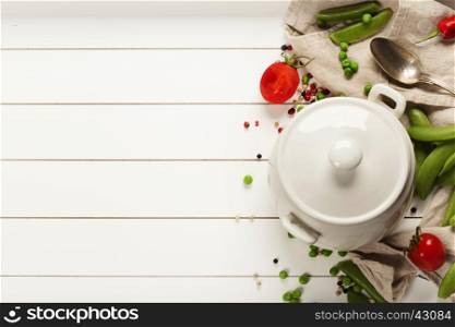 White cooking pot and ingredients for soup or stew on white rustic background, top view