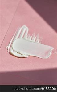 White cosmetic cream on a pink background.