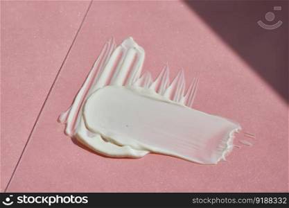 White cosmetic cream on a pink background.