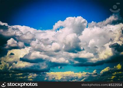 White Cumulus Clouds And Grey Storm Clouds Gathering On Blue Sky