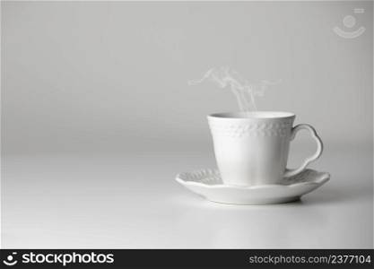 White cup and saucer of tea or coffee with steam on white background. Ceramic cup or mug with hot drink. Mock-up classic porcelain utensils. copy space.. White cup and saucer of tea or coffee with steam on white background. Ceramic cup or mug with hot drink. Mock-up classic porcelain utensils. copy space