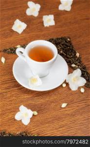 white cup and saucer with jasmine flowers on a wooden table. background