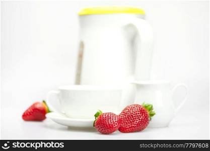 white cup, milk jug, teapot and strawberries isolated on white