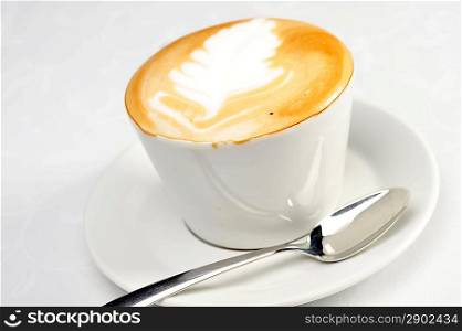 White cup of cappuccino with brown and white foam on top. Object on white