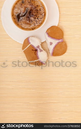 White cup of coffe with funny bikini underwear shape gingerbread cake cookie sweet dessert with white icing and violet decoration border or frame on beige bamboo mat background