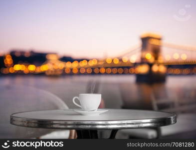 White cup of coffee at the cafe table with skyline view