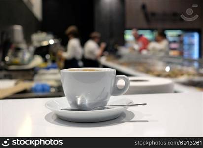 White cup of coffee over blurred cafe interior