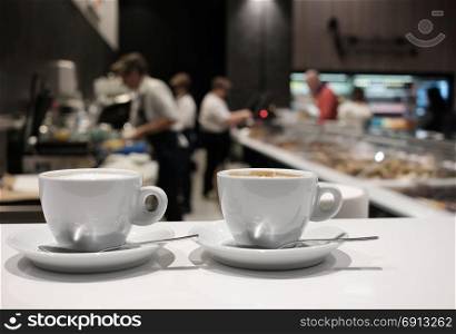 White cup of coffee over blurred cafe interior