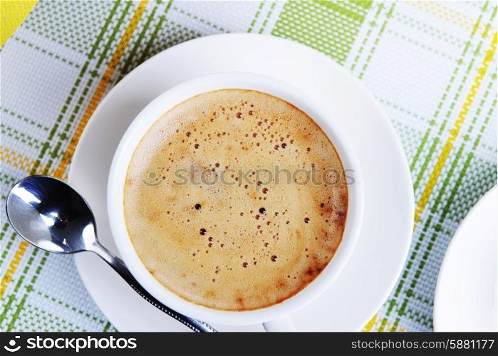 White cup of coffee with spoon on saucer