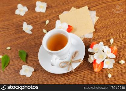 white cup of green tea. jasmine flowers with strawberry halves. texture blank for writing. still life