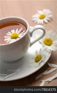 white cup of herbal tea and camomile flowers