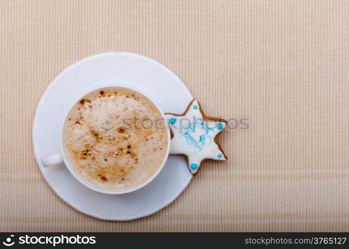White cup of hot beverage drink coffee cappuccino latte and homemade gingerbread cake star with icing and blue decoration. Christmas. Holiday concept.