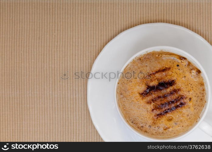 White cup of hot beverage drink coffee cappuccino latte with froth on brown background. Studio shot.