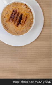 White cup of hot beverage drink coffee cappuccino latte with froth on brown background. Studio shot.