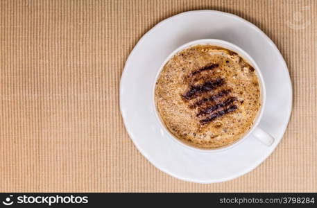 White cup of hot beverage drink coffee cappuccino latte with froth on brown background. Studio shot.