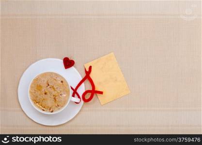 White cup of hot beverage drink coffee cappuccino latte with heart shape symbol love and blank paper card space for text message. Valentine&#39;s day.