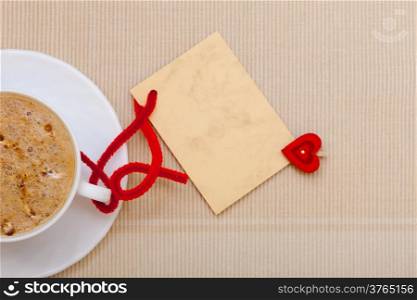 White cup of hot beverage drink coffee cappuccino latte with heart shape symbol love and blank paper card space for text message. Valentine&#39;s day.