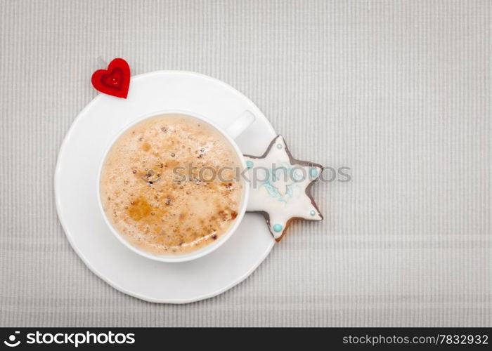 White cup of hot beverage drink coffee cappuccino latte with homemade gingerbread cake star with icing and blue decoration and red heart symbol love. Christmas. Holiday concept.