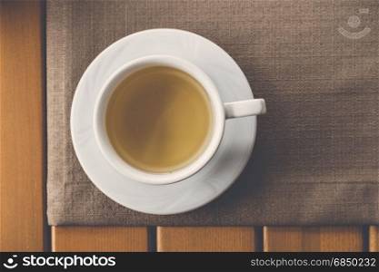 White cup of tea over wooden background