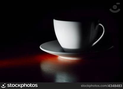 white cup on saucer in dark