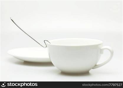white cup, saucer and spoon isolated on white