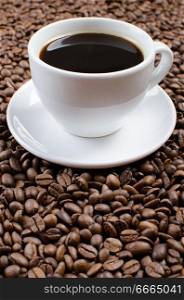 White cup with black coffee on the coffee beans.