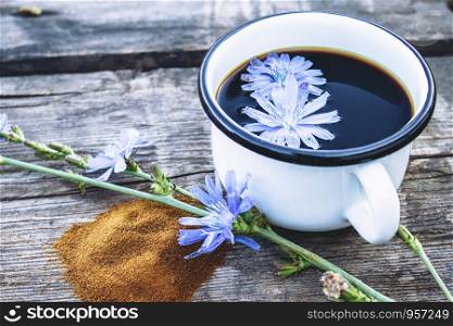 White cup with chicory drink and flowers near chicory powder. Tea from chicory. Healthy eating concept. Coffee substitute.. White cup with chicory drink and flowers near chicory powder. Tea from chicory. Healthy eating concept.