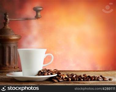 White cup with coffee beans and grinder on a red background