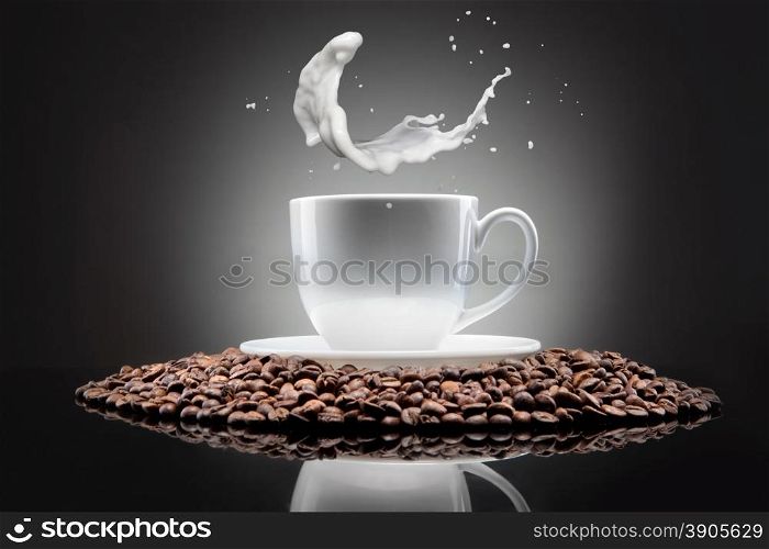 white cup with coffee beans and milk splash on black