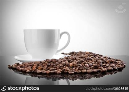 white cup with coffee beans on white