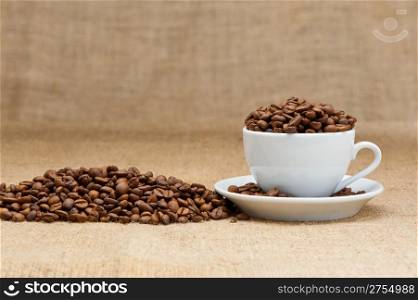White cup with coffee grains. Grunge background