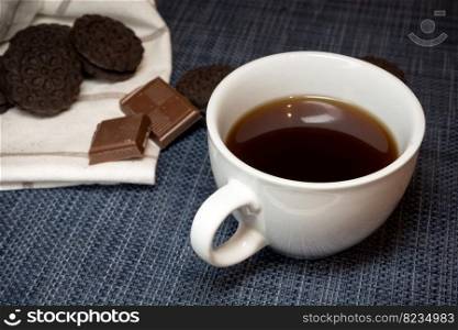 White cup with dark coffee and sweets, close-up