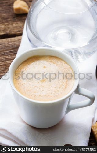 white cup with fresh espresso coffee and glass of water. cup of coffee