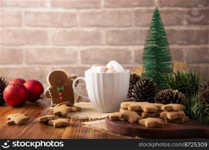 White cup with hot chocolate with marshmallows and Christmas Homemade gingerbread man cookie,  traditionally made at wintertime and the holidays.