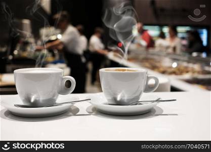 White cups of coffee over blurred cafe interior