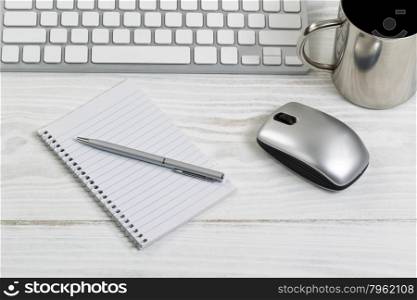 White desktop with partial keyboard, mouse, coffee cup, paper and pen. Horizontal layout with silver color theme.
