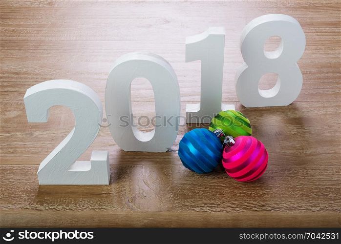 White digits 2018 with Christmas balls on rustic wooden background as concept of New Year and Christmas.